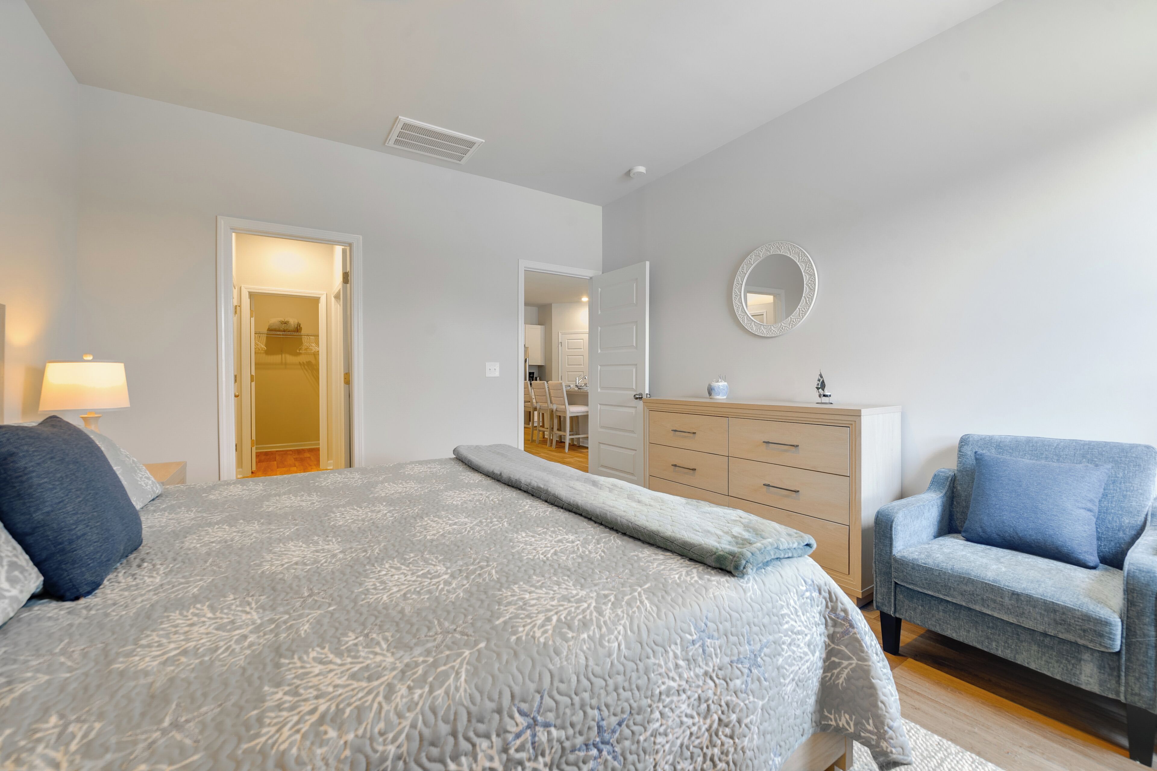 Ein Schlafzimmer mit Bett, Kommode, Stuhl und Spiegel.