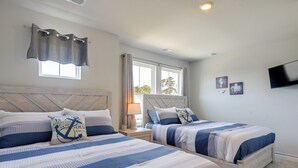 Un dormitorio con dos camas, una ventana, un televisor y una mesita de noche con lámpara.