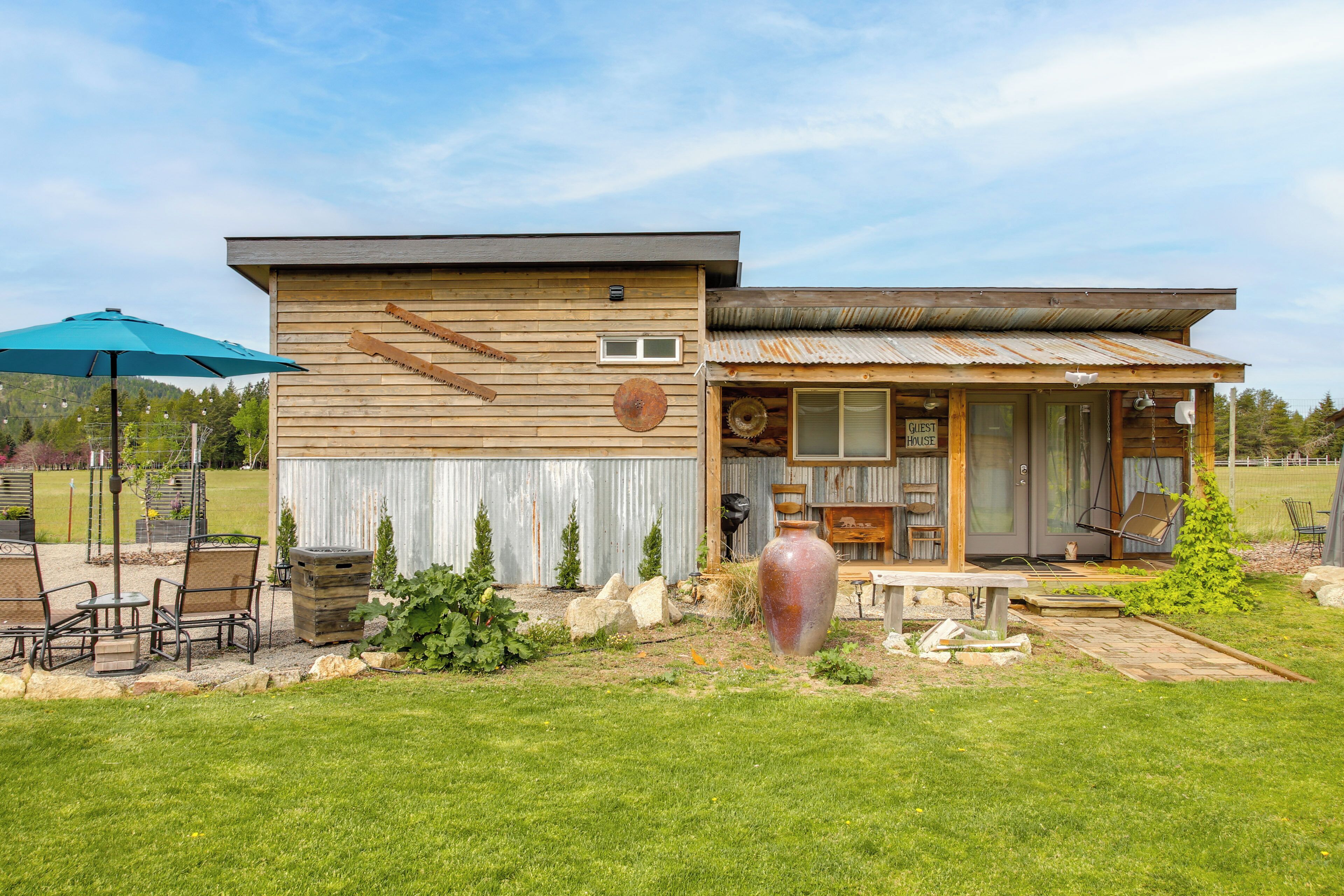 Une maison à deux étages dotée d’un patio, d’un grand vase et de mobilier d’extérieur.