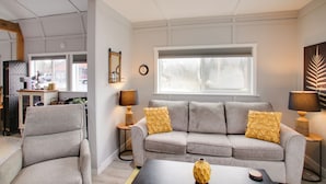A modern living room with a grey sofa, two yellow patterned cushions, a black coffee table, and a wooden side table with a lamp. - 6 Mi to Lake Pend Oreille! Cozy Cabins w/ Views (Athol)