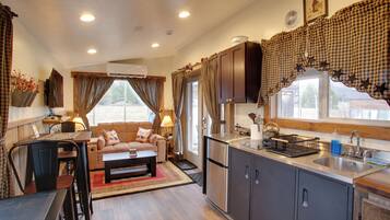 A compact living space with a kitchenette, a dining area, and a seating area with a sofa and coffee table.