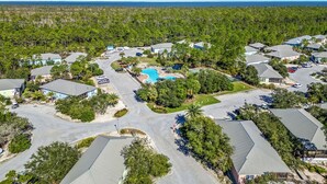 Une vue aérienne d’un quartier résidentiel avec des maisons, une piscine et un ciel bleu dégagé.