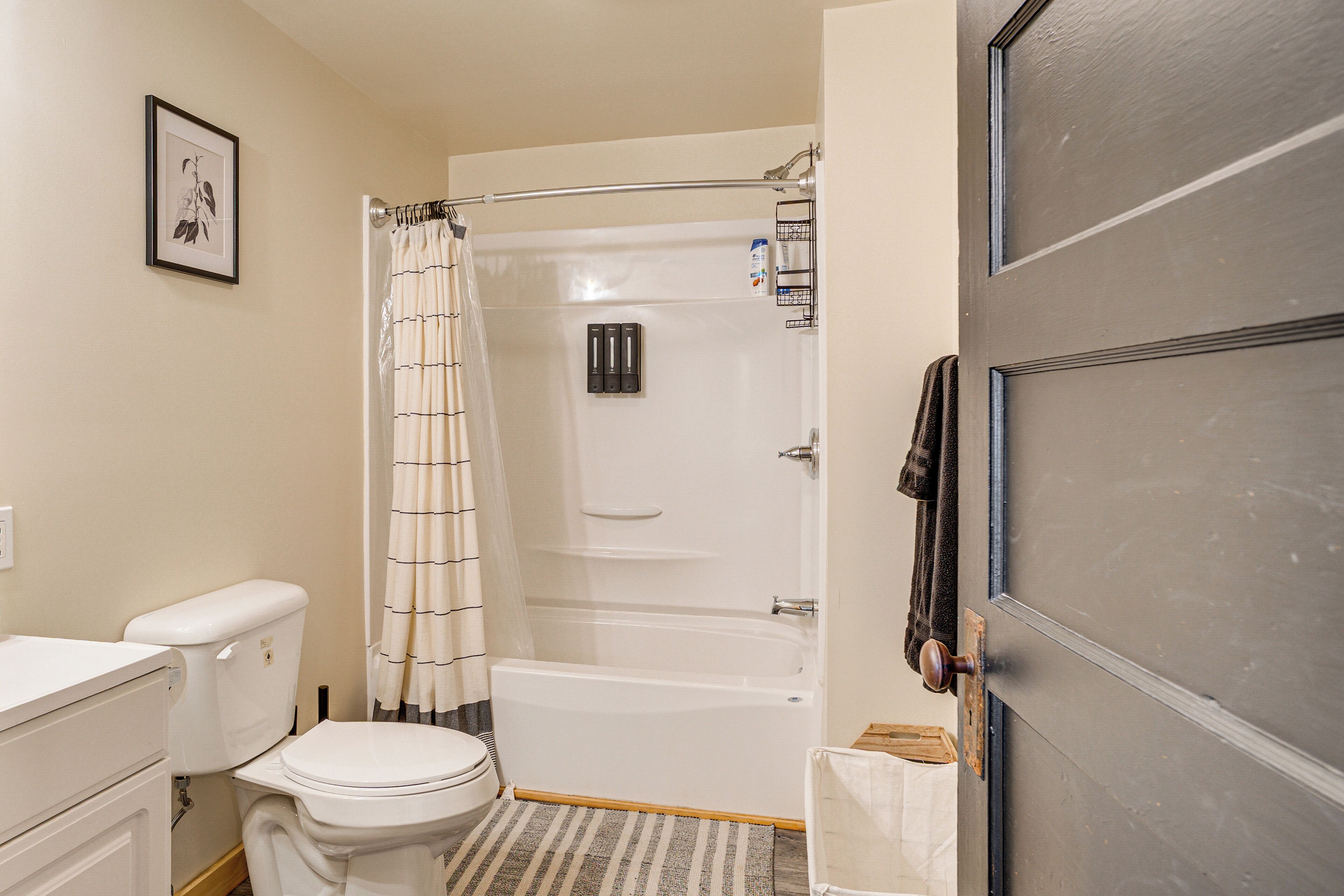 A bathroom with a toilet, bathtub, shower curtain, and a towel rack.
