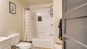 A bathroom with a toilet, bathtub, shower curtain, and a towel rack.