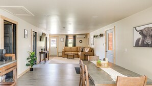 A modern kitchen with a dining area, a sofa, and a bull-themed artwork on the wall.