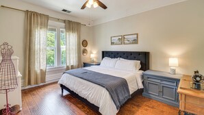 A bedroom with a bed, nightstands, a dresser, a ceiling fan, and a window with curtains. - Historic Home in Downtown Sonora! (Sonora)