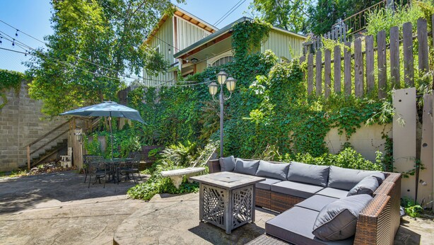 A patio with a wicker sofa, a table, and an umbrella. - Historic Home in Downtown Sonora! (Sonora)