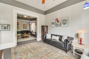 A living room with a black leather sofa, a patterned rug, and a fireplace.