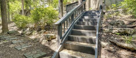 A wooden staircase leading up a stone wall, surrounded by trees and natural vegetation.