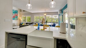 A modern kitchen with a dishwasher, a sink, and a dining area with a table and chairs. - Lakefront Bliss w/ Dock + Fire Pit! Ozarks Home (Osage Beach)