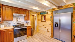Une cuisine avec des meubles en bois, un réfrigérateur en acier inoxydable et une pancarte sur laquelle on peut lire : « Venez tous manger. »