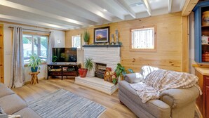 Un salon chaleureux avec une cheminée, un téléviseur et des fauteuils confortables.