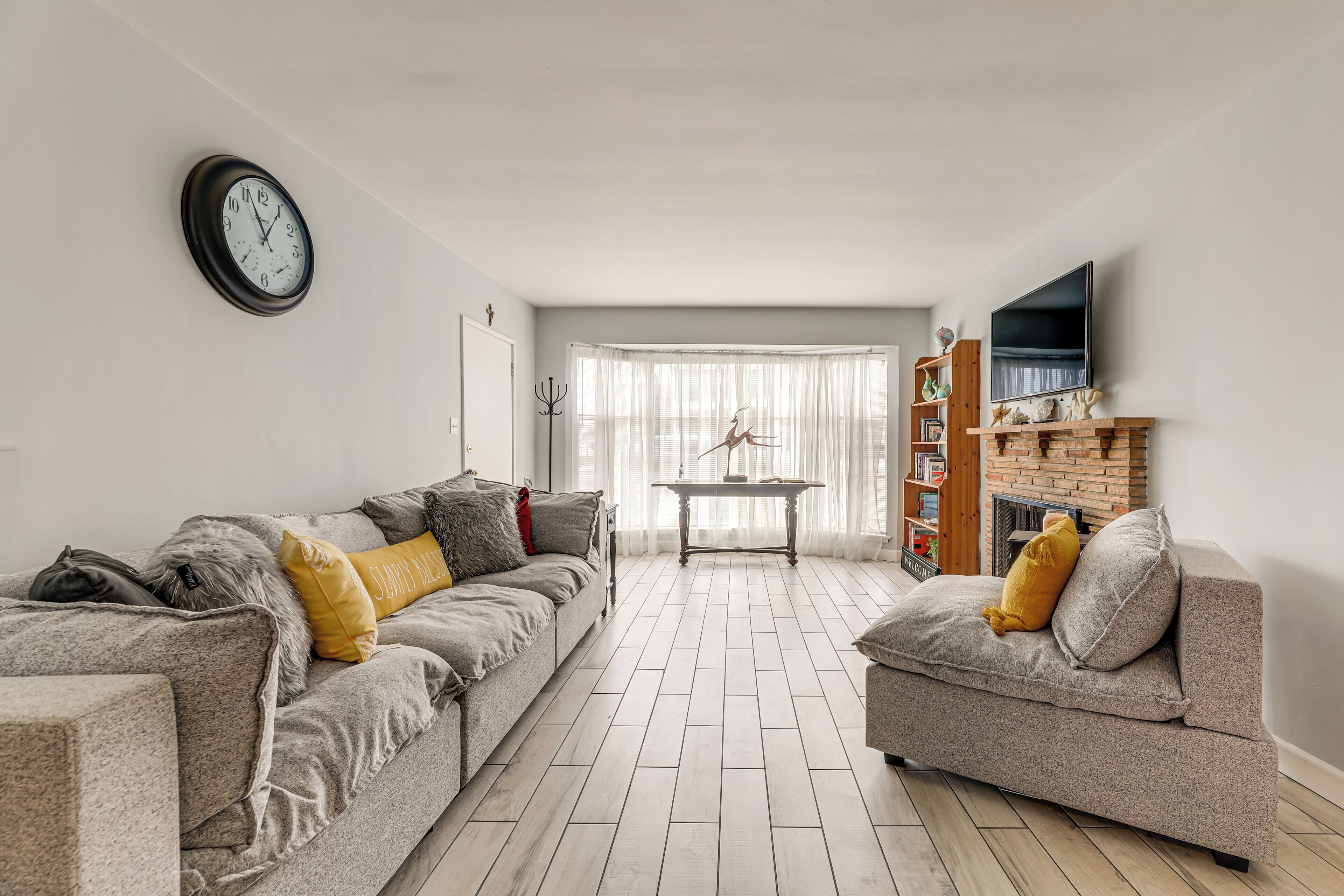 Een woonkamer met twee banken, een klok, een open haard en een televisie.