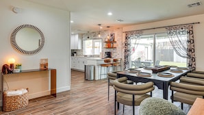 A modern kitchen with a dining area, wooden flooring, and a large window with curtains. - Backyard Oasis! Group Retreat Near Tempe Town Lake (Tempe)