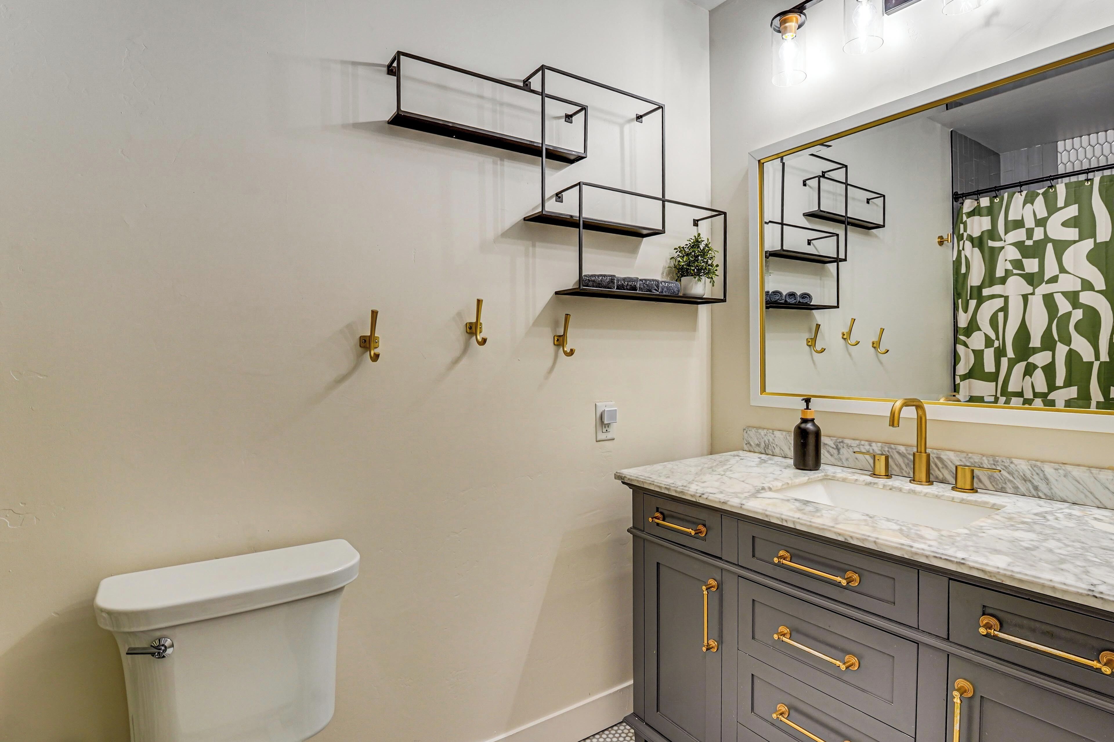 Une salle de bain comprenant des toilettes, un lavabo avec un plan de travail en marbre et un meuble-lavabo avec des tiroirs et un miroir.