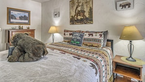 Een slaapkamer met een bed, een lamp, een dressoir en wanddecoratie.