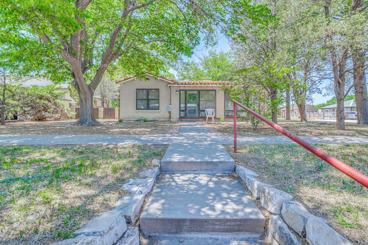 A house with a concrete pathway leading to the front door, surrounded by trees and a clear sky.