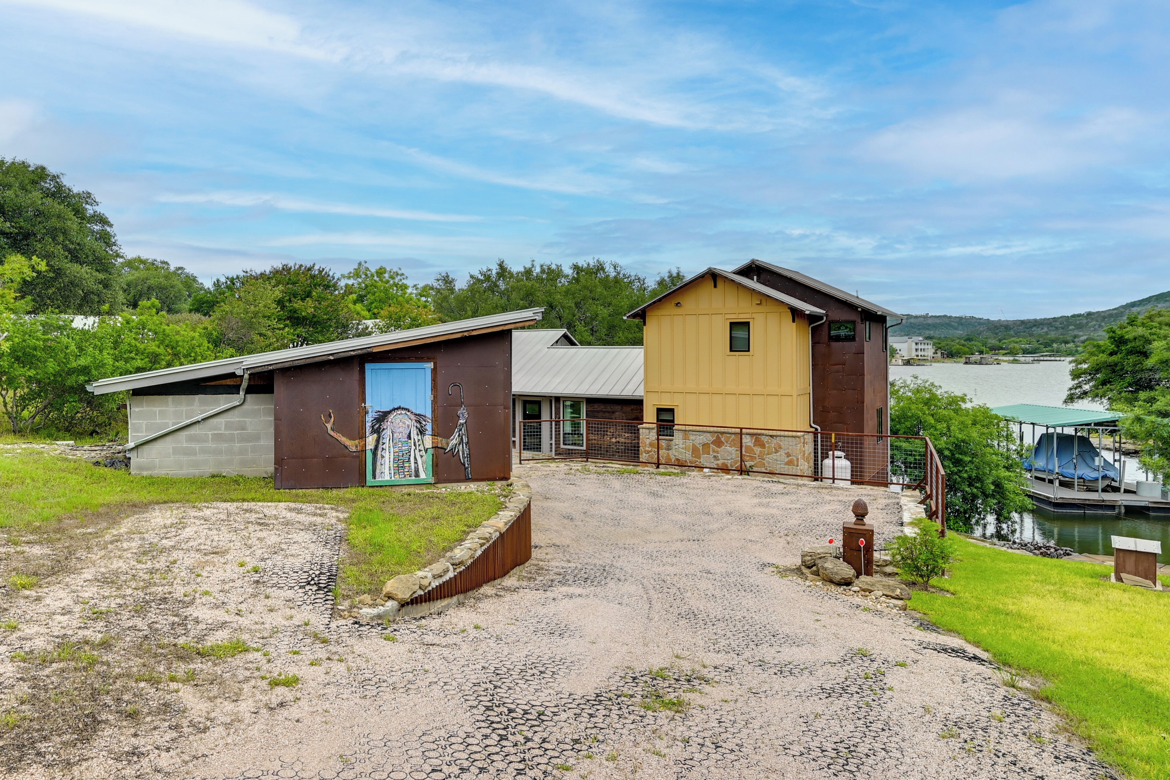 A building with a gravel driveway, a small shed, and a mural on the wall.