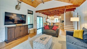 A spacious living area with a wooden ceiling, a television, a sofa, and a staircase leading to an upper level. - Fishing Dock & Mtn Views! Buchanan Lake Family Gem (Burnet)