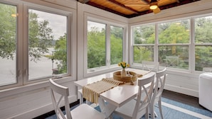 A room with a white table and chairs, large windows, and a ceiling fan. - Fishing Dock & Mtn Views! Buchanan Lake Family Gem (Burnet)
