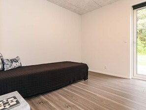 A room with a single bed, a small table, and a view through a glass door. - 5 Star Holiday Home in Skals (Skals)