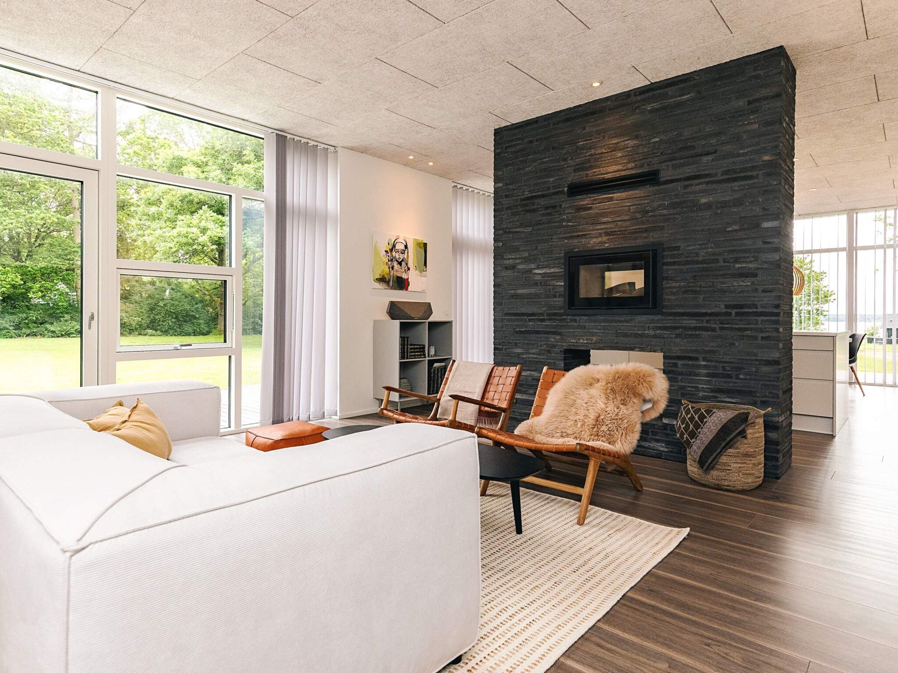 A modern living room with a white sofa, a fireplace, and a large window.