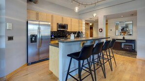 Una cocina moderna con una isla central, electrodomésticos de acero inoxidable y taburetes de bar.