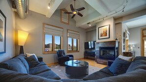 Un salón con chimenea, ventilador de techo y televisor.