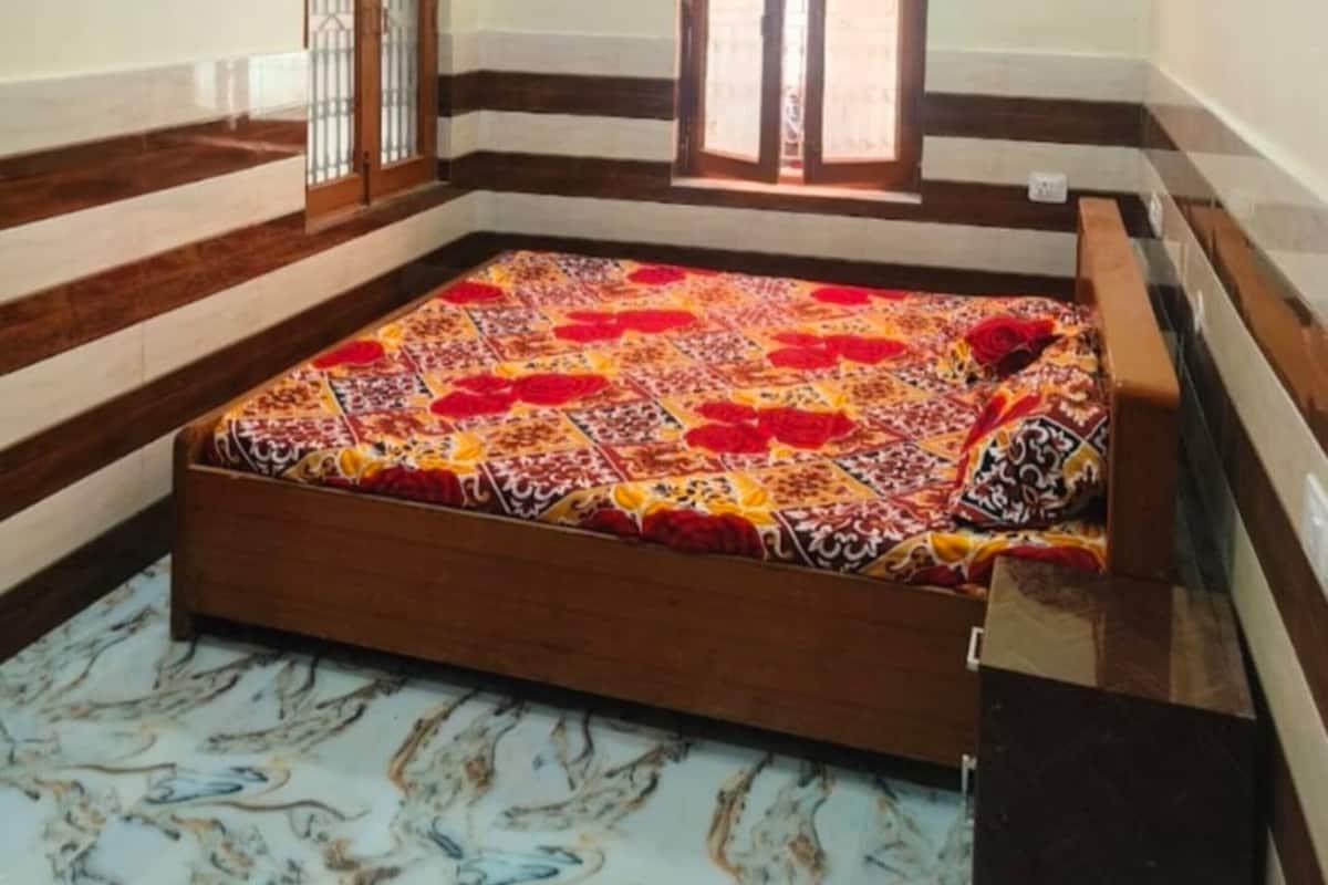 A room with a bed, a window, a ceiling fan, and a patterned floor.