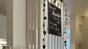 A breakfast buffet with a sign, fruit, and beverages. - CozyNook Boutique Homestay (Xuan Huong - Da Lat)