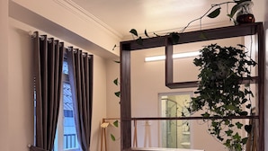 A hotel room with a bed, a sofa, a small table, a mirror, and a potted plant. - CozyNook Boutique Homestay (Xuan Huong - Da Lat)