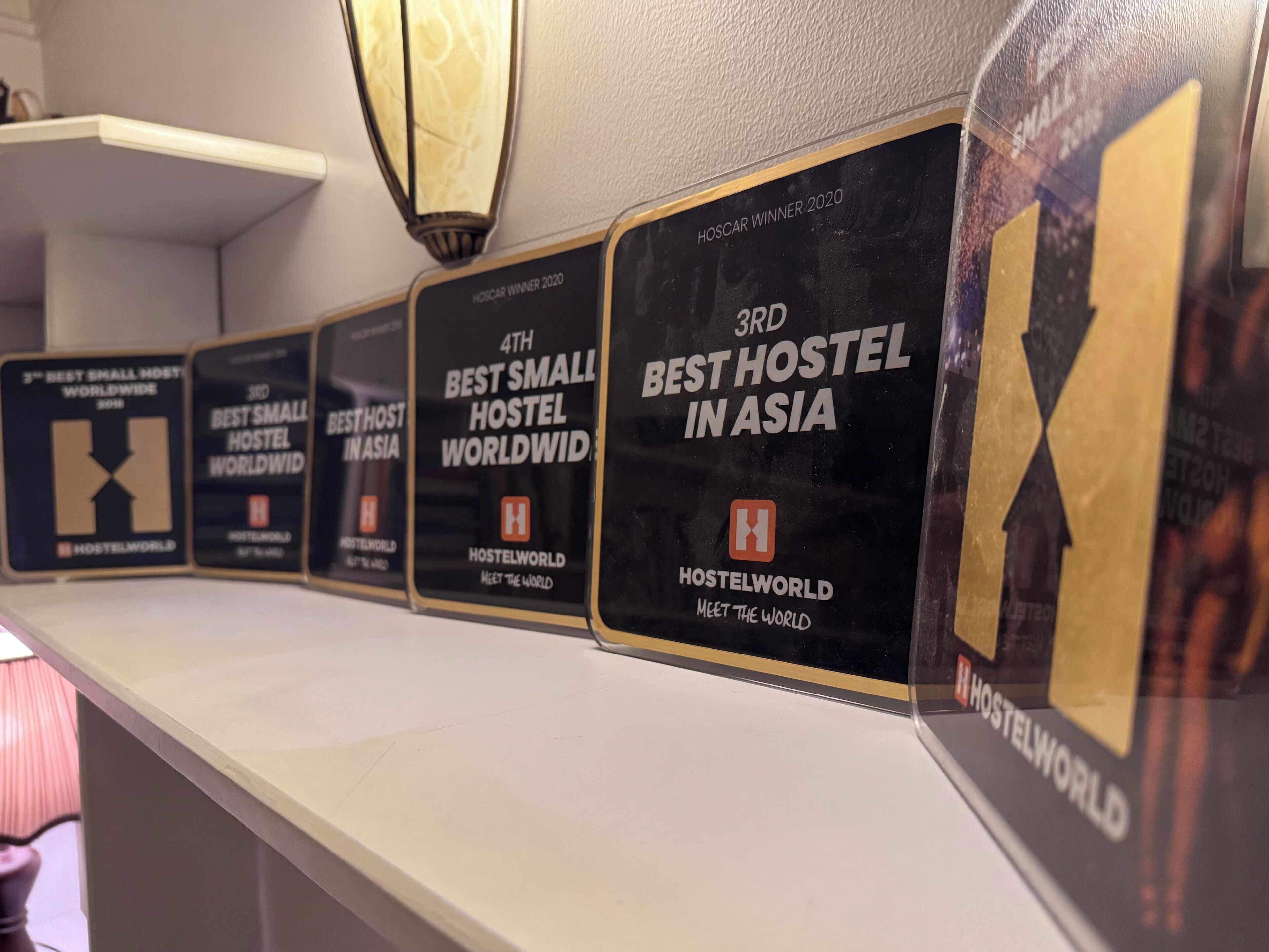 A row of award plaques on a wall, each with text indicating rankings for hostel accommodations.