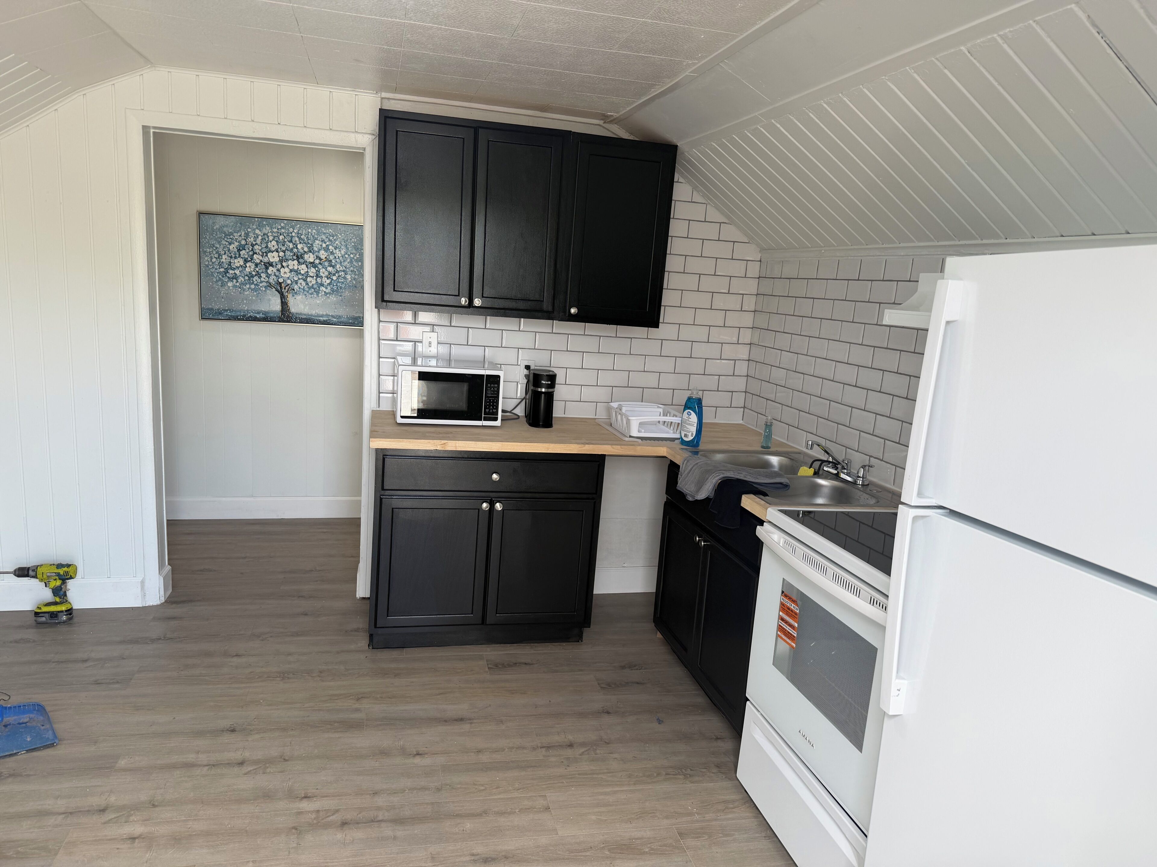 A compact kitchen with a microwave, coffee maker, and a refrigerator.