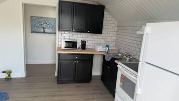 A compact kitchen with a microwave, coffee maker, and a refrigerator.
