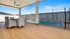 A covered patio with a pool, wicker furniture, and a view of the pool. - Ultra Modern Luxury Retreat with Pool in Northcrest Estate, sleeps 9 (Berrimah)