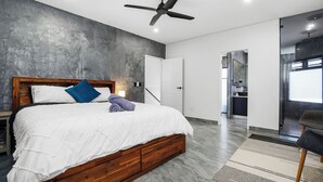 A modern bedroom with a wooden bed, a ceiling fan, and a view into the kitchen. - Ultra Modern Luxury Retreat with Pool in Northcrest Estate, sleeps 9 (Berrimah)