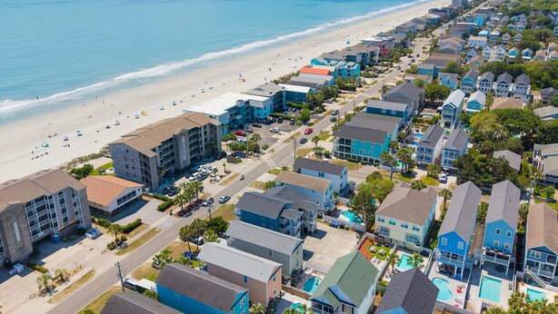 Una zona residenziale sul lungomare, con case direttamente sulla spiaggia, una piscina e vista libera sull'oceano.