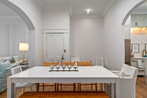 Un comedor con una mesa blanca, sillas de mimbre y una puerta blanca.