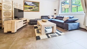 Uma sala de estar com televisão, sofá, mesa de centro e um quadro na parede.