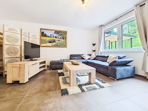 Ein Wohnzimmer mit Fernseher, Sofa, Couchtisch und einem Bild an der Wand.