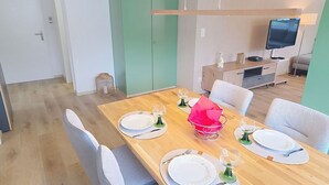 A dining area with a wooden table set for four, chairs, a television, and a cabinet in the background. - Cosy apartment for 4 people with WIFI, TV, balcony, pets allowed and panoramic view (Haag (rheintal))