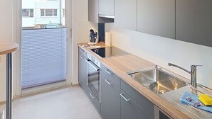 A modern kitchen with grey cabinets, a wooden countertop, a built-in oven, and a stainless steel sink. - Cosy apartment for 4 people with WIFI, TV, balcony, pets allowed and panoramic view (Haag (rheintal))