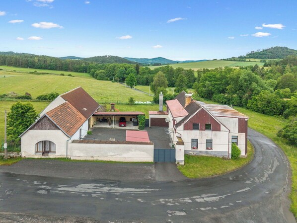 A rural property with a barn, a garage, and a driveway leading to a house.