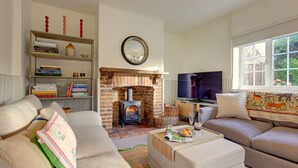 Ein Wohnzimmer mit Kamin, Fernseher, Sofa, Bücherregal und Fenster.