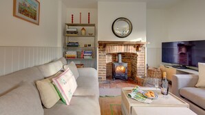 Ein Wohnzimmer mit einer Couch, einem Kamin, einem Fernseher und einem Bücherregal.