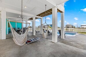 Ein überdachter Außenbereich mit zwei Hängematten, einem Pool und Blick auf Häuser.