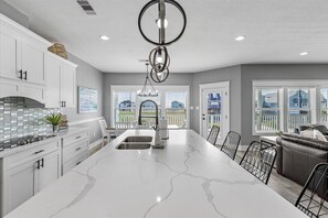 A modern kitchen with a large island, white cabinetry, and a view of the outside. - Insta-Ahhh * Private Pool • Pet Friendly Oasis * Steps to Beach (Galveston)
