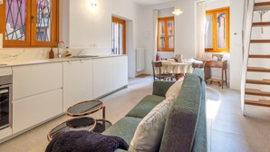 A modern kitchen with white cabinets, a dining area with a table and chairs, and a green sofa in the living area. - Cosy apartment for 4 people with WIFI and balcony (Brovello)