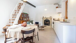A dining area with a table set for four, a staircase, a fireplace, and a kitchen area with a sink and countertop. - Cosy apartment for 4 people with WIFI and balcony (Brovello)