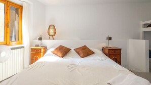 A bedroom with a bed, two bedside tables, a lamp, a wall-mounted lamp, and a window with curtains. - Cosy apartment for 4 people with WIFI and balcony (Brovello)